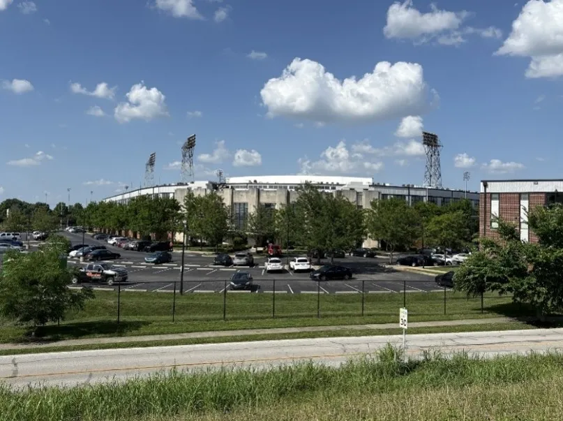 Three stadium lights stand above the  main entrance to Stadium Lofts, which is partially obscured by trees